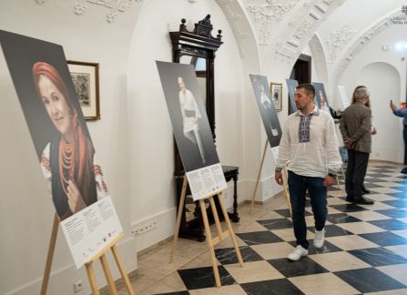 Fotografia. Wernisaż wystawy piękno jedności. ludzie oglądają fotografie stojące na sztalugach pod ścianą holu głównego willi Decjusza.